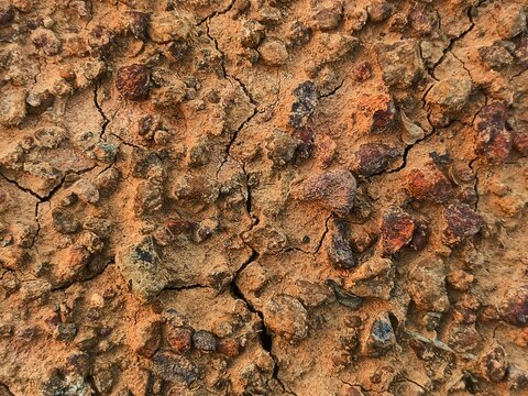 Dry cracked red soil texture with small gravel stones