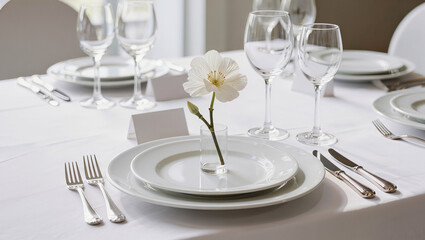 Fototapeta premium Elegant white table setting with single white flower in bud vase, minimal fine dining place setting with crystal wine glasses and copy space