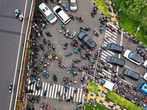 Aerial view of Jalan Outer Ring Road in Kecamatan Cengkareng, showing a busy intersection crowded with motorcycles and cars waiting at a crosswalk in Daerah Khusus Ibukota, Indonesia.