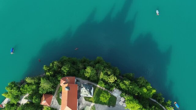 Top down aerial drone view of Bled Island with the Church of the Assumption surrounded by Lake Bled in Slovenia, showcasing the island from directly above.