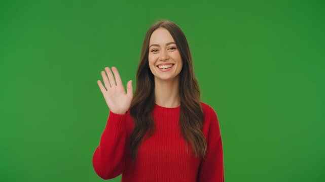 Woman waving hello on a green screen background with subtle camera zoom and soft lighting