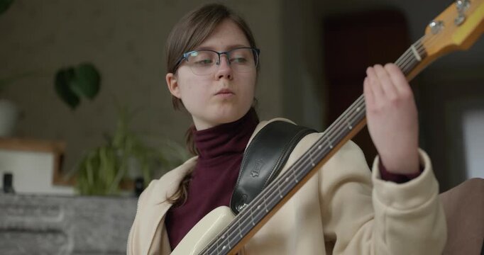 Musician Girl Play Bass Guitar at Home. Young Female Playing Music. 4K 10-bit