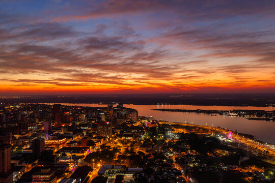 Aerial view of Costanera Norte and the Asuncion skyline along the Paraguay River at sunset, with city lights illuminating the urban landscape in Asuncion, Asuncion, Paraguay.