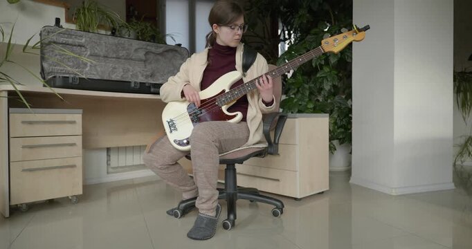 Musician Girl Play Bass Guitar at Home. Young Female Playing Music. 4K 10-bit