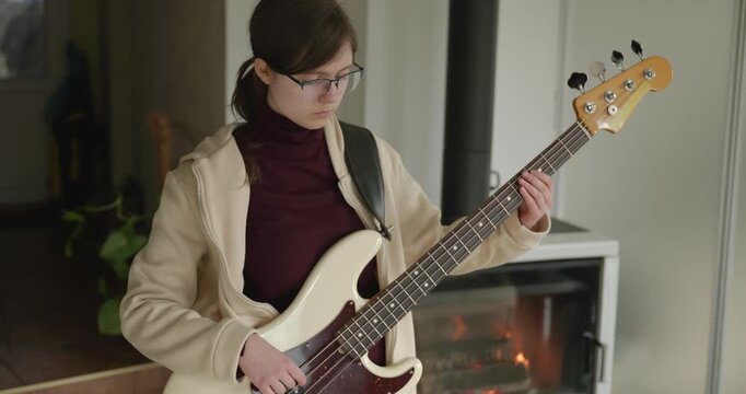 Musician Girl Play Bass Guitar at Home. Young Female Playing Music. 4K 10-bit