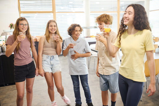 Group of teens in a school cafeteria sharing drinks and enjoying together