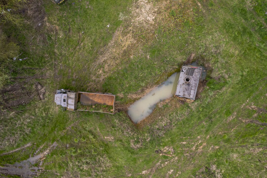 Aerial view of an abandoned army truck and tank partially submerged in a muddy field with a pool of water in Belgium.
