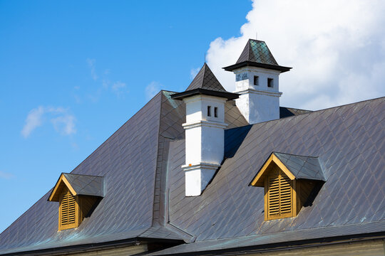 Diamond-pattern roof with twin turrets and dormer windows, blue sky