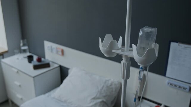 Intravenous drip stand with saline bottle dripping in empty hospital room. Footage for healthcare marketing, clinical services promotion, and medical documentaries