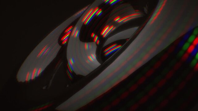 Close-up detail of glossy dark torus geometry reflecting glowing RGB pixel arrays in a hypnotic 3D animation loop with chromatic aberration