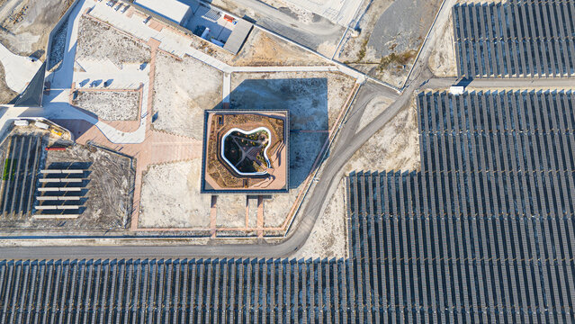 Aerial view of the Karapinar Solar Power Plant featuring rows of photovoltaic panels and a central modern building with a landscaped courtyard in Karapinar, Konya, Turkiye.
