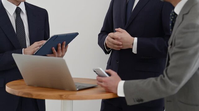 ノートパソコンとタブレットを使って打ち合わせを行う30代と50代の日本人ビジネスマン
