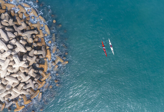 Aerial view of two kayaks paddling near the concrete breakwater of Herzliya Beach in Herzliya, Tel Aviv District, Israel.