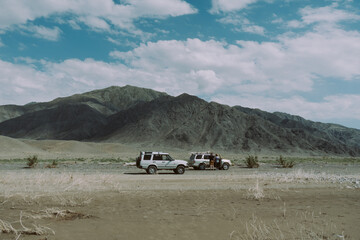 Off-road cars camping in wild mountain valley under cloudy blue sky, adventure travel concept © Anastasia