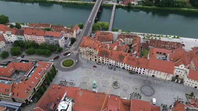 Aerial drone view of Maribor Main Square, the historic Old Bridge over the Drava River, red tile roofs and city center on a summer day in Slovenia.
