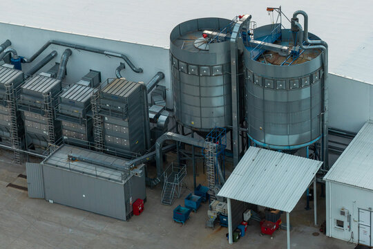 Aerial view of centralized dust collection and filtration units with industrial ventilation ducts and metal silos at a manufacturing facility in Poland.