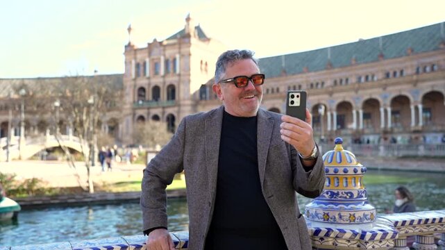 Mature tourist man video calling from plaza de espa&ntilde;a in seville
