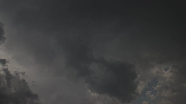 Time-lapse of gray rain clouds moving across the sky with light shower and blue gaps between clouds