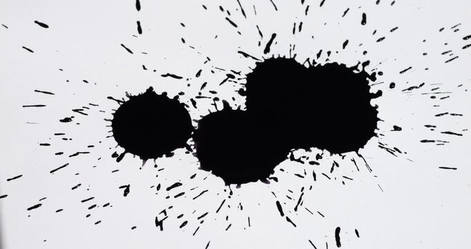 Ink splashes on a white sheet of paper. Black paint stains on a white background.