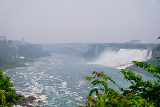 View of Niagara Falls with the Rainbow Bridge in the background and mist rising from the water in Niagara Falls, Ontario, Canada.