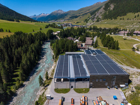 Aerial view of the Upper Engadine Wastewater Treatment Plant with solar panels on its roof, situated next to the Inn river in the alpine valley of S-chanf, Grisons, Switzerland.