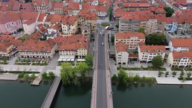 Aerial drone view of the Old Bridge over the Drava River leading to the historic center of Maribor with riverside promenade and red tile roofs in Slovenia.