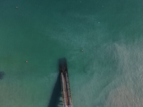 Aerial view of a pier extending into the turquoise waters of Mother Ivy's Bay with calm sea and clear visibility United Kingdom.