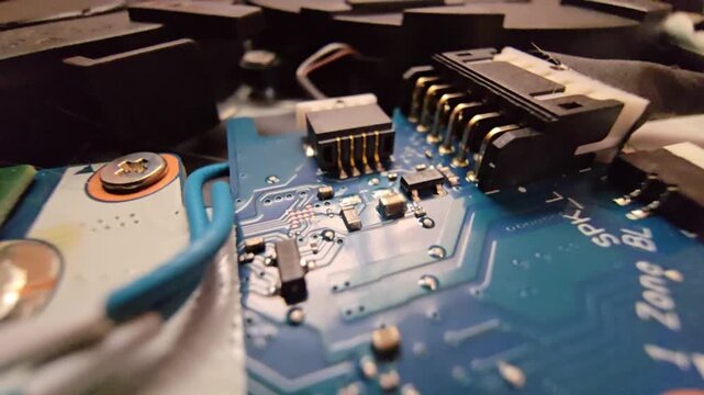 Macro close-up shot of a laptop circuit board, showcasing internal wire connectors, speaker plug sockets, and intricate electronic components.