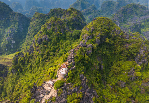 Aerial view of Mua cave with stone stairs winding up the lush limestone karst mountains in Nam Hoa Lu, Ninh Binh, Vietnam.