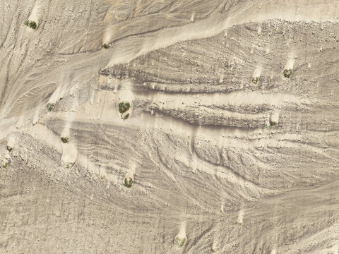 Aerial view of the Skeleton Coast featuring intricate patterns of small sand hummocks and sparse desert vegetation in a dry riverbed of the Kunene Region, Namibia.