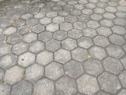 Top view of a weathered grey hexagonal concrete paving stone path.