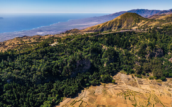 Aerial view of Cova Crater Panoramic Viewpoint featuring lush green forests, terraced agricultural fields, and a distant coastline in Faja de Cima, Porto Novo, Cabo Verde.