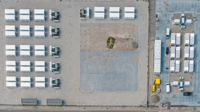 Aerial view of a battery energy storage system site with rows of white storage containers, electrical equipment, and gravel surfaces in Dronten, Flevoland, Netherlands.