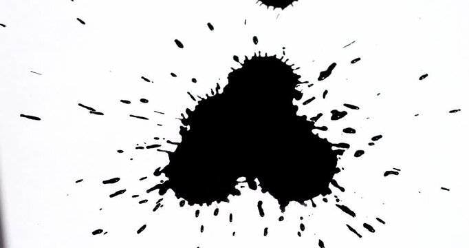 Ink splashes on a white sheet of paper. Black paint stains on a white background.