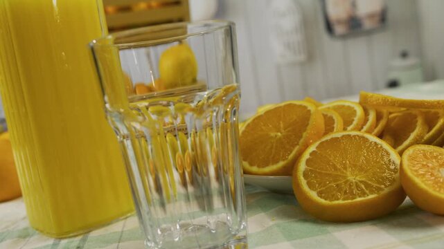 Closeup, slow motion shot of juice being poured into glass near orange slices