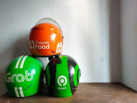Malang, Indonesia - July 11, 2026: Three helmets used by Indonesian ride-hailing and delivery services: Grab, ShopeeFood, and Gojek. Helmet for rider. Gig worker. Freelancer. Freelance.