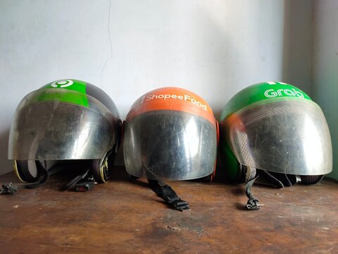 Malang, Indonesia - July 11, 2026: Three helmets used by Indonesian ride-hailing and delivery services: Grab, ShopeeFood, and Gojek. Helmet for rider. Gig worker. Freelancer. Freelance.