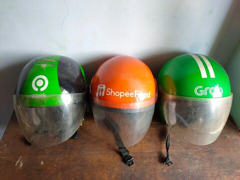 Malang, Indonesia - July 11, 2026: Three helmets used by Indonesian ride-hailing and delivery services: Grab, ShopeeFood, and Gojek. Helmet for rider. Gig worker. Freelancer. Freelance.