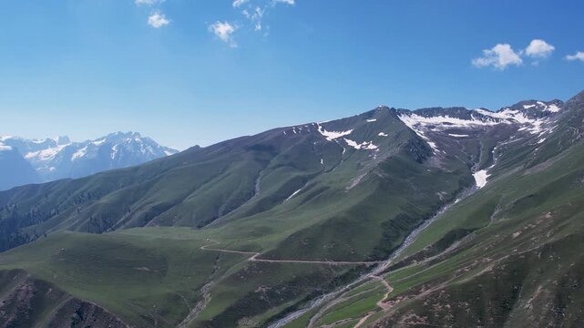 Snowcapped peaks rise above green mountain slopes near Badgoi Pass, Upper Dir, Khyber Pakhtunkhwa, Pakistan