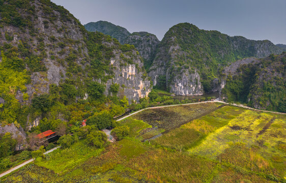 Aerial view of Tam Coc Bich Dong with limestone karst mountains, lush green rice fields, and a winding river in Nam Hoa Lu, Ninh Binh, Vietnam.