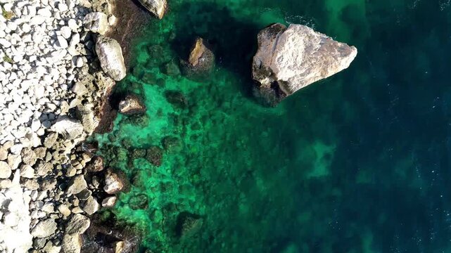 Aerial view of rocky coastline with clear turquoise sea water along the shore in Calp, Valencian Community, Spain.