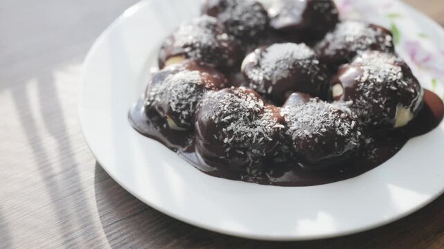 Close-up of profiteroles with chocolate sauce on white plate