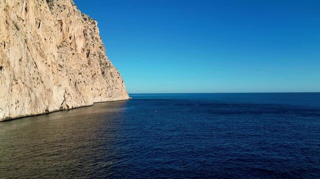 Aerial view of Penyal d'Ifac limestone cliff rising from the deep blue Mediterranean Sea in Calp, Valencian Community, Spain.