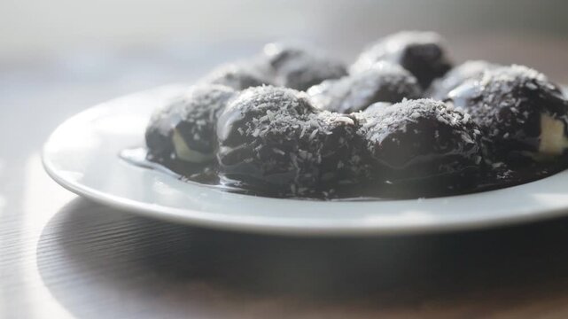 Close-up of profiteroles with chocolate sauce on white plate