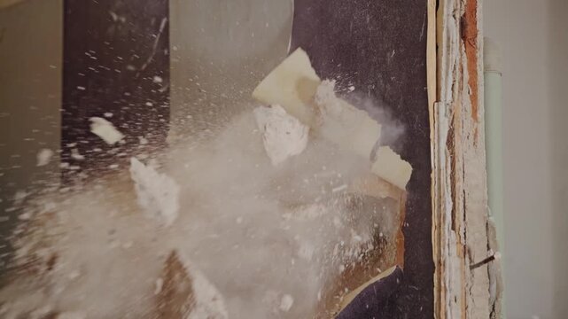 Slow motion captures dramatic impact as dust and rubble explode from the wall