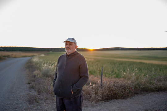 Mature man standing in rural field contemplating sunset