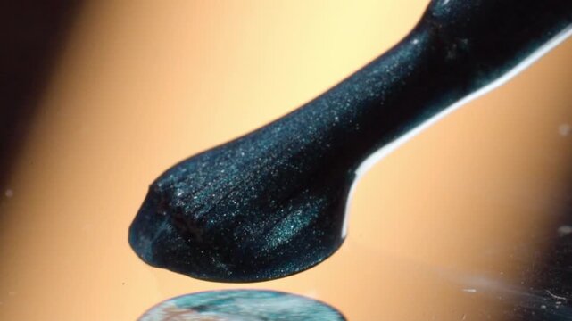 Macro close up of metallic cosmetic cream on black spatula. Shimmering beauty product displays smooth texture and reflective finish in fine detail