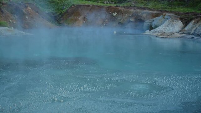 Sulfurous water bubbling and steaming in a volcanic geothermal hot spring in Jigokudani, a famous valley located above the town of Noboribetsu Onsen on Hokkaido island, Japan