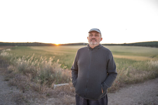 Mature man standing in field at sunset enjoying nature