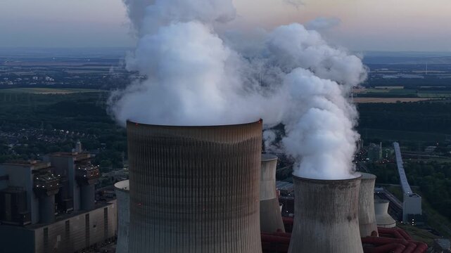 Aerial view of Power Plant Niederausem in Germany at dusk, showing a massive fossil fuel station with smoking cooling towers and industrial energy infrastructure.